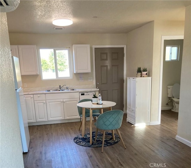 kitchen featuring visible vents, wood finished floors, white appliances, white cabinets, and a sink