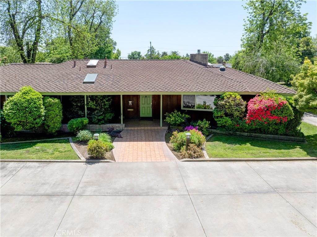 ranch-style house with a chimney, a shingled roof, and a front yard