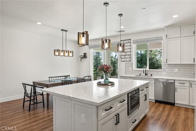 kitchen featuring dark wood-style floors, a sink, backsplash, and appliances with stainless steel finishes