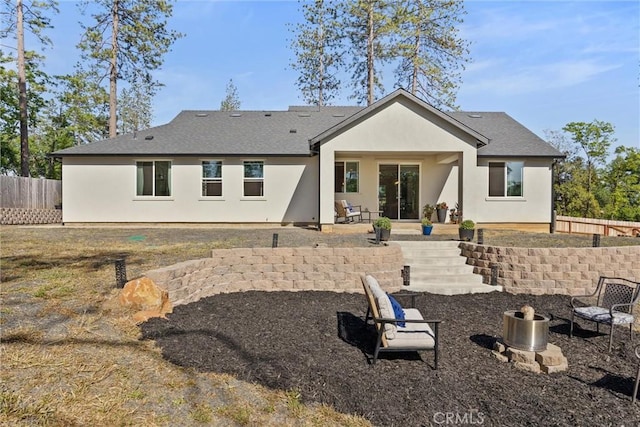 rear view of house with an outdoor fire pit, a patio area, roof with shingles, stucco siding, and fence