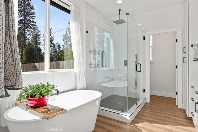 bathroom with a stall shower, a wealth of natural light, and wood finished floors