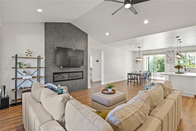 living area with recessed lighting, a fireplace, light wood-style flooring, lofted ceiling, and ceiling fan with notable chandelier