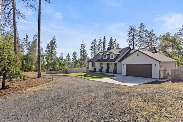 view of front of home featuring driveway, stucco siding, fence, a front lawn, and a garage