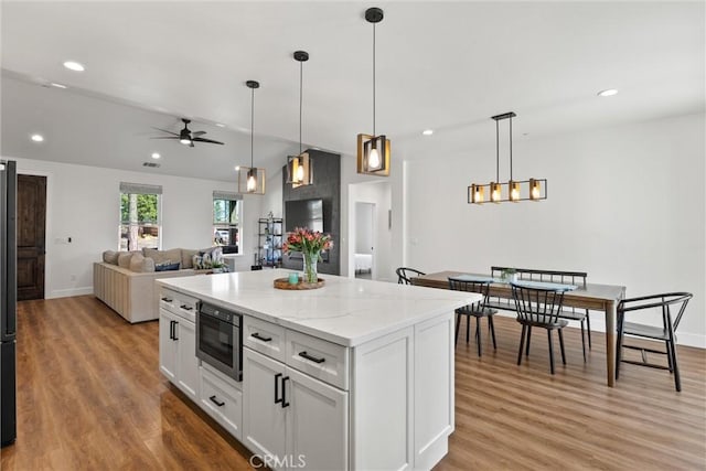 kitchen featuring white cabinetry, a ceiling fan, light wood-style floors, and a kitchen island
