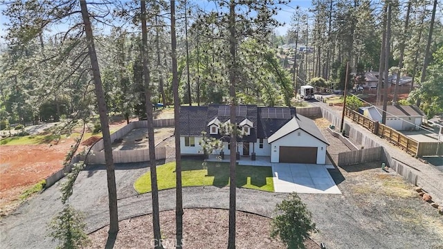 view of front of property featuring driveway, solar panels, an attached garage, and fence