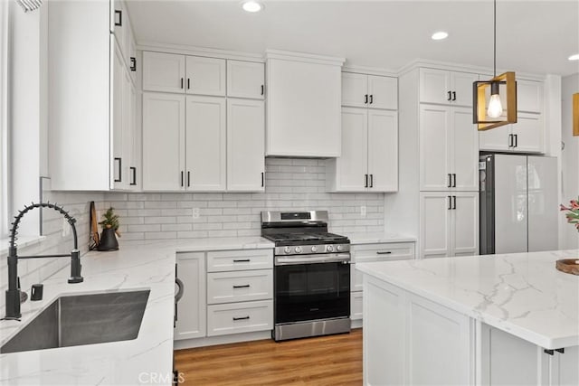 kitchen featuring gas stove, a sink, white cabinets, and decorative backsplash