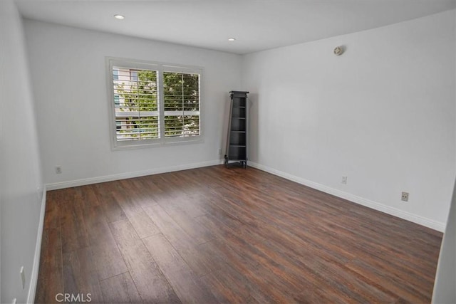 empty room featuring baseboards, recessed lighting, and wood finished floors