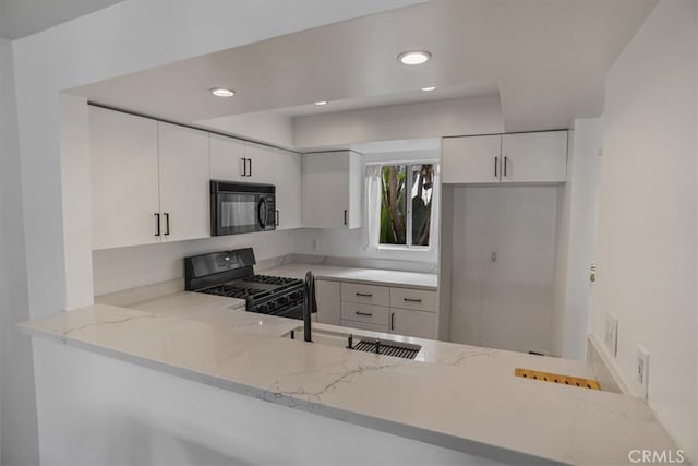 kitchen with white cabinets, light stone countertops, a sink, recessed lighting, and black appliances