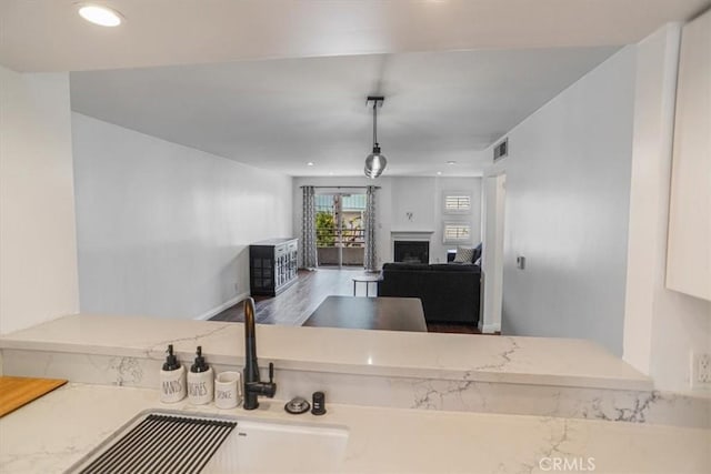 kitchen with hanging light fixtures, a fireplace, recessed lighting, and visible vents
