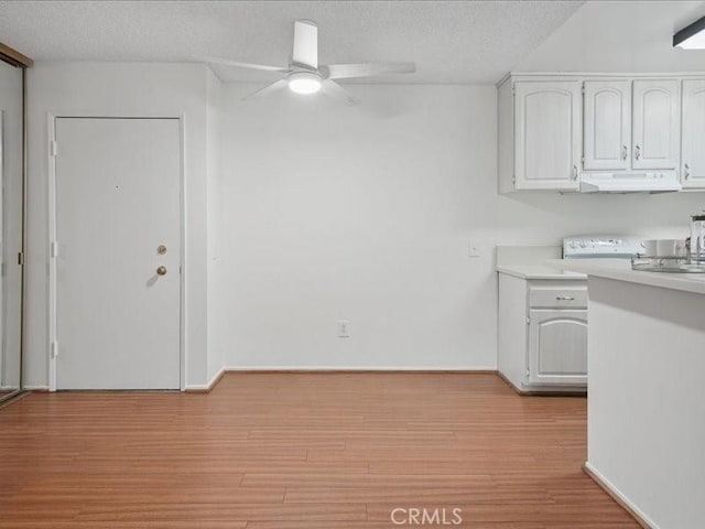 23515 Lyons Ave Unit 286, Valencia, CA 91355 - kitchen with a ceiling fan, under cabinet range hood, white cabinetry, light countertops, and a textured ceiling