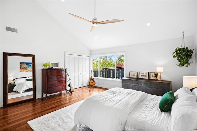 bedroom with baseboards, visible vents, wood finished floors, and high vaulted ceiling