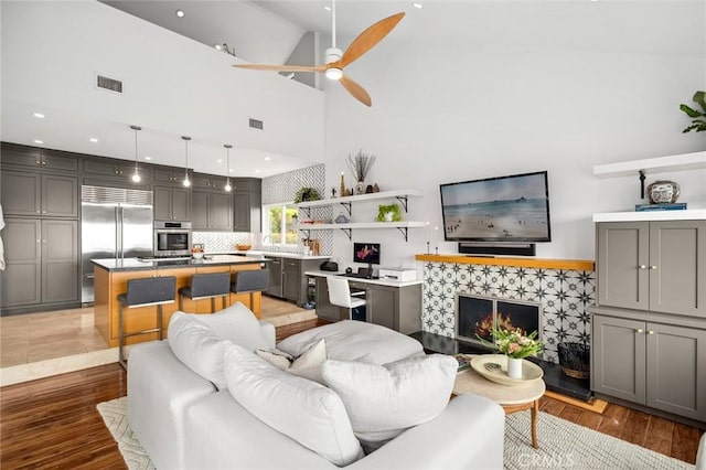 living area featuring ceiling fan, light wood-type flooring, and visible vents