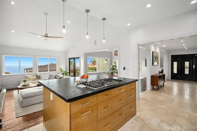 kitchen with dark countertops, open floor plan, recessed lighting, high vaulted ceiling, and stainless steel gas cooktop