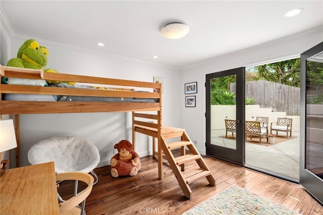 bedroom with wood finished floors, ornamental molding, and access to exterior