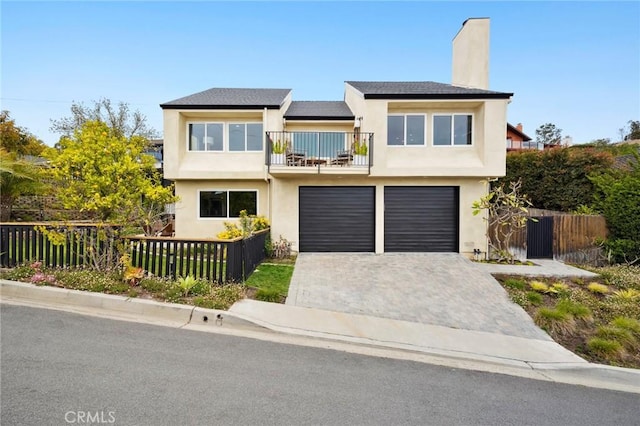 view of front facade with a chimney, fence private yard, a balcony, and an attached garage