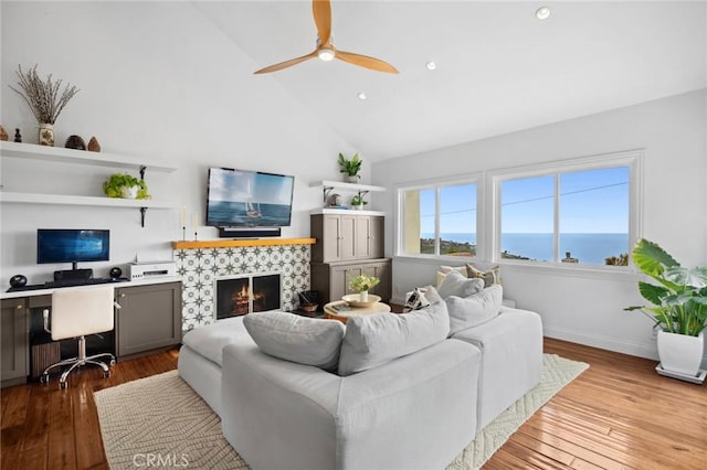 living area featuring a ceiling fan, high vaulted ceiling, hardwood / wood-style flooring, and a fireplace