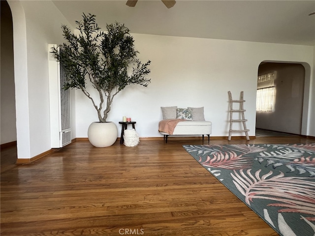 sitting room with baseboards, arched walkways, a ceiling fan, and wood finished floors
