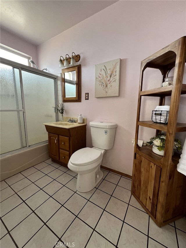 bathroom featuring tile patterned flooring, combined bath / shower with glass door, toilet, and vanity