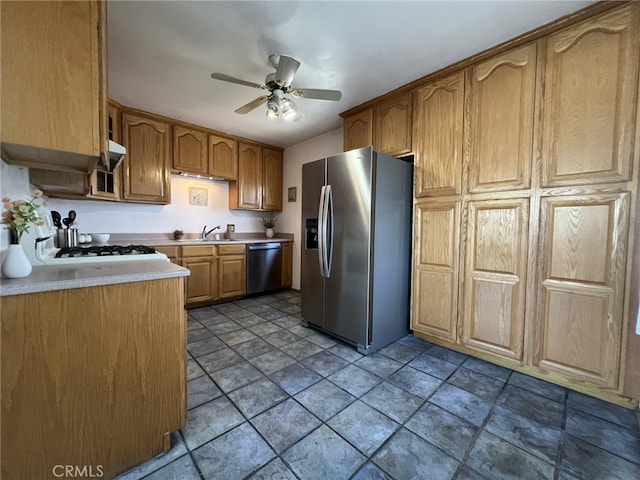 kitchen featuring appliances with stainless steel finishes, a sink, light countertops, stone finish floor, and a ceiling fan