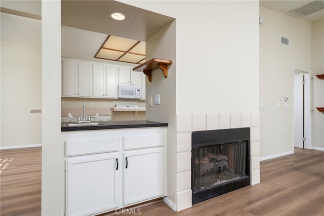 432 W Caldwell Ct, San Dimas, CA 91773 - kitchen featuring white microwave, wood finished floors, white cabinets, dark countertops, and a sink