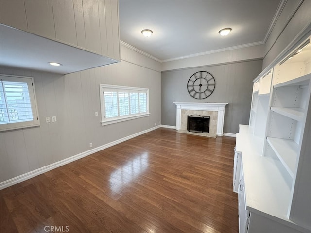 unfurnished living room featuring dark wood-type flooring, a healthy amount of sunlight, a tiled fireplace, and ornamental molding