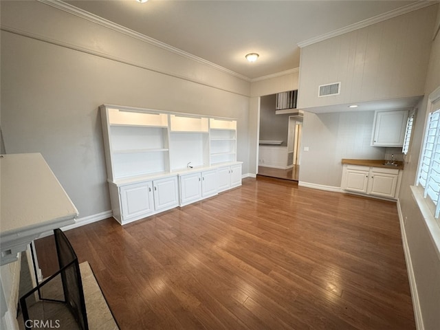 unfurnished dining area with a sink, crown molding, visible vents, and wood finished floors