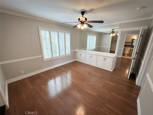 unfurnished room with dark wood finished floors, baseboards, ornamental molding, and a ceiling fan
