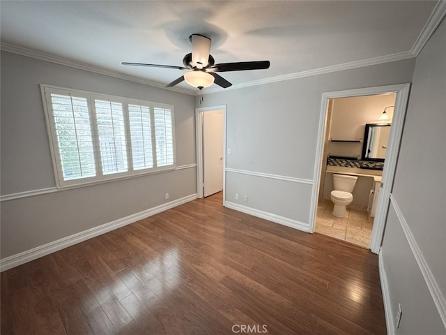 unfurnished bedroom with ornamental molding, connected bathroom, wood finished floors, and baseboards