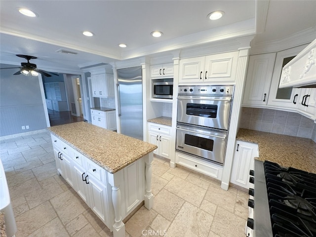 kitchen featuring built in appliances, tasteful backsplash, a ceiling fan, visible vents, and white cabinets