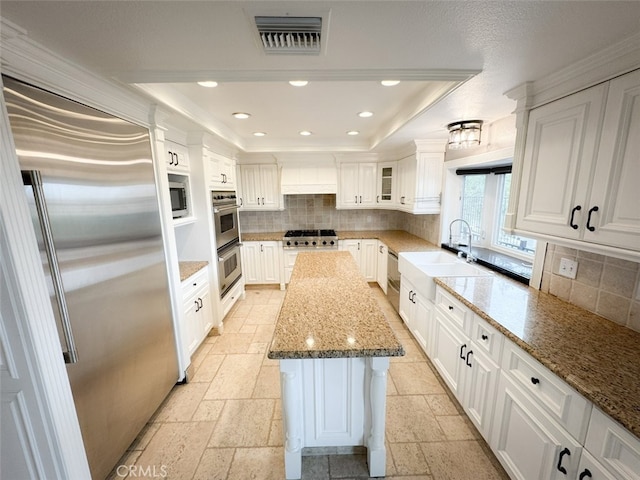 kitchen featuring a raised ceiling, decorative backsplash, visible vents, and a center island