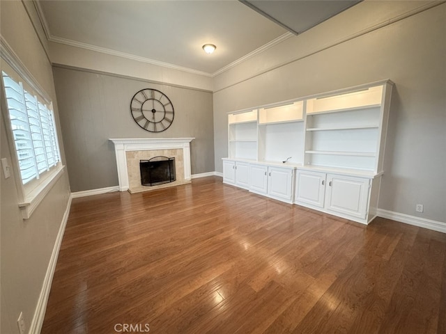 unfurnished living room featuring baseboards, wood finished floors, crown molding, and a fireplace