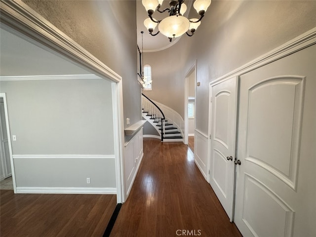 foyer with dark wood-style floors, stairway, a notable chandelier, crown molding, and baseboards