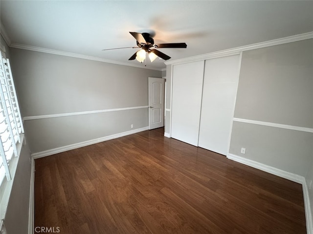unfurnished bedroom with crown molding, baseboards, dark wood finished floors, and a closet