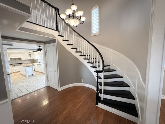 stairway with wood finished floors and ceiling fan with notable chandelier