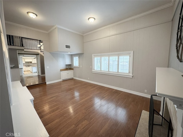 unfurnished living room with dark wood-style floors, visible vents, ornamental molding, and baseboards