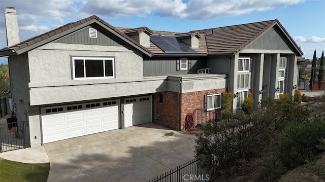 view of front facade with a tiled roof, fence, a garage, solar panels, and concrete driveway
