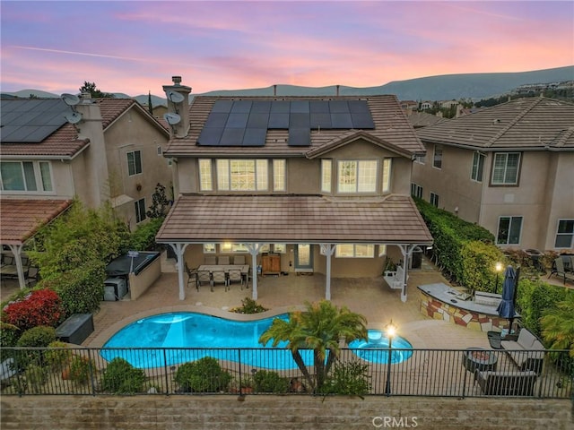 20704 Campania Ln, Porter Ranch, CA 91326 - back of house with a fenced backyard, stucco siding, outdoor dining area, roof mounted solar panels, and outdoor dry bar