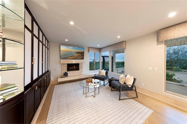 living room featuring light wood-type flooring, recessed lighting, and a lit fireplace