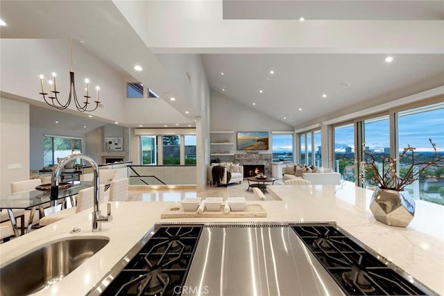 kitchen featuring open floor plan, recessed lighting, a warm lit fireplace, and a sink