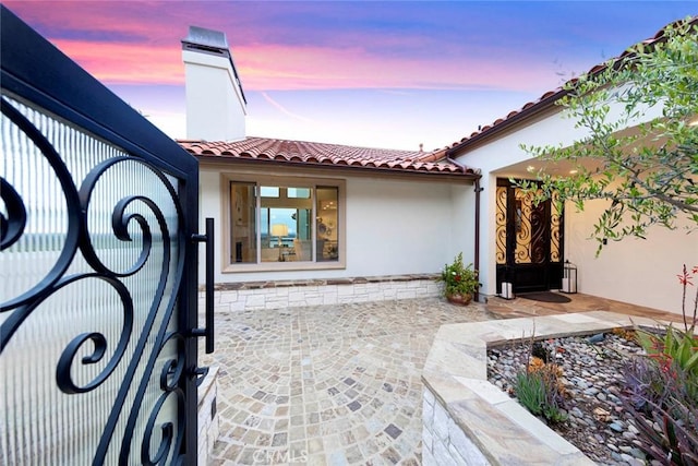 entrance to property featuring stucco siding and a tile roof