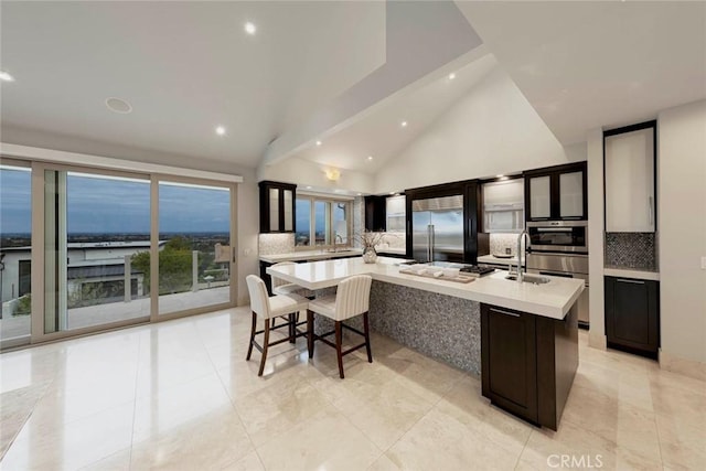 kitchen with decorative backsplash, a sink, stainless steel appliances, light countertops, and a large island