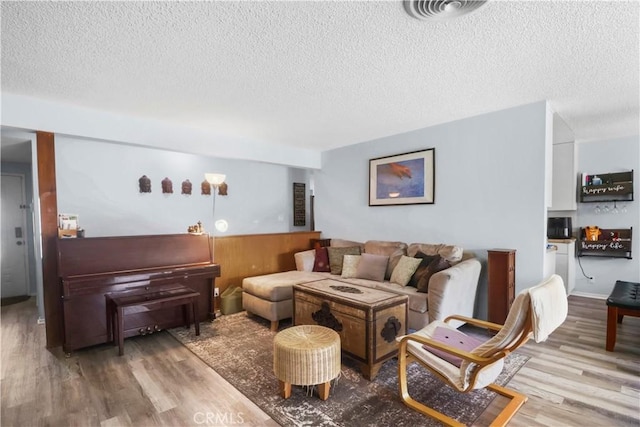 living room with visible vents, a textured ceiling, and wood finished floors