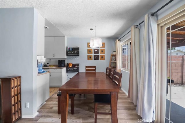 dining space featuring a textured ceiling and light wood finished floors