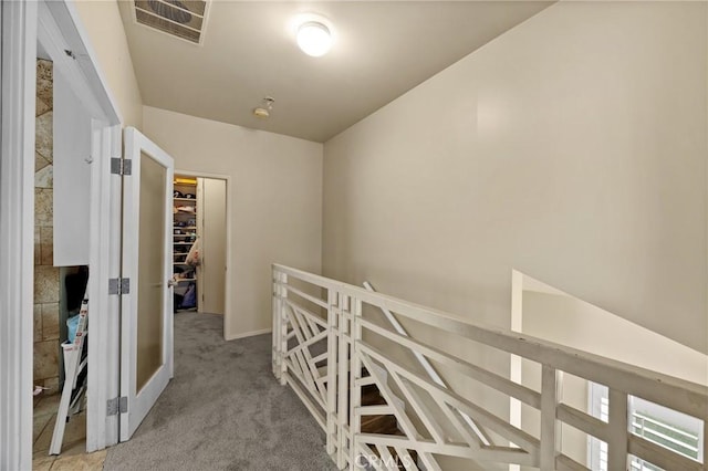 hall featuring baseboards, visible vents, an upstairs landing, and carpet