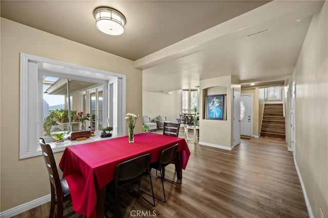 dining area featuring baseboards, wood finished floors, and stairs