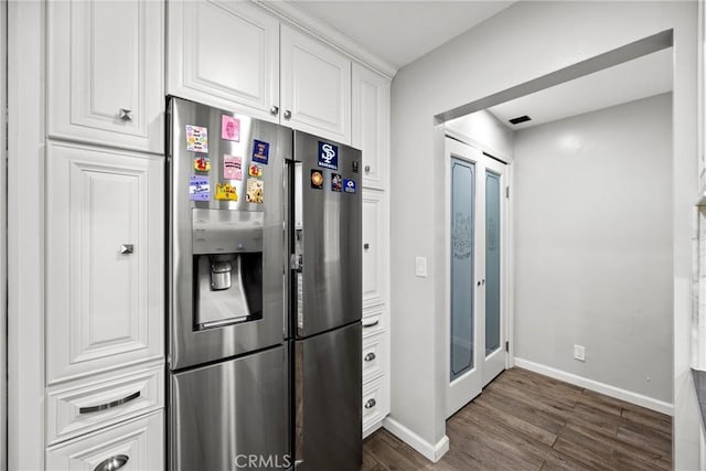 kitchen with dark wood-style floors, stainless steel refrigerator with ice dispenser, white cabinetry, and baseboards