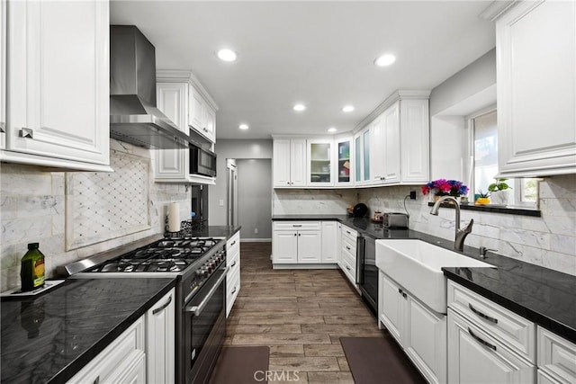 kitchen with range with gas stovetop, white cabinetry, wall chimney exhaust hood, and a sink