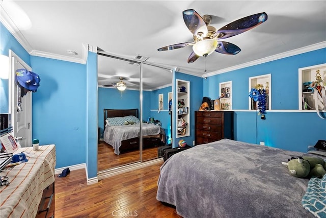 bedroom featuring wood finished floors, a closet, ornamental molding, ceiling fan, and baseboards