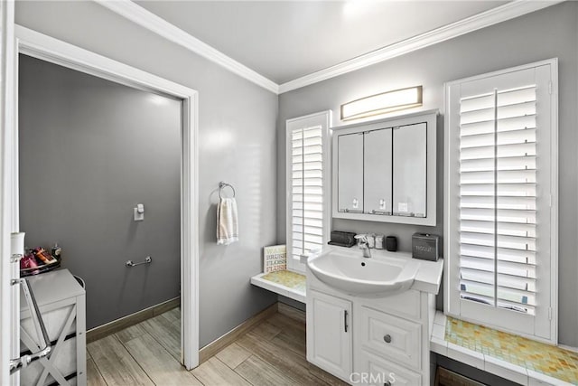 bathroom with ornamental molding, vanity, wood finished floors, and baseboards