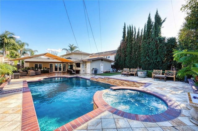 view of swimming pool featuring a grill, a pool with connected hot tub, a patio, and an outdoor hangout area